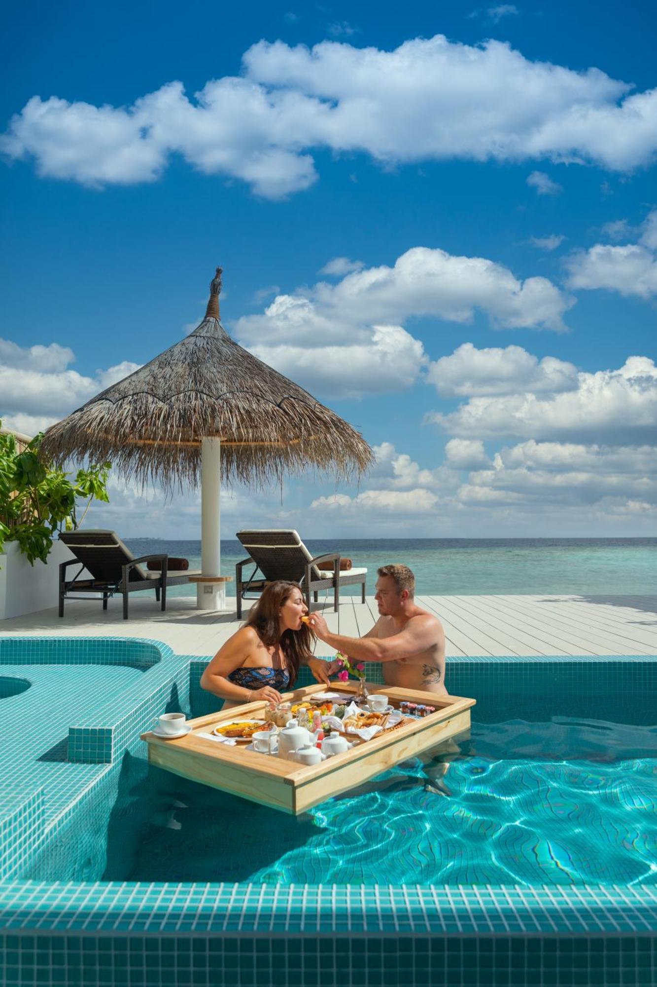 منتجع مالاهيني كودا باندوس هولهومالي المظهر الخارجي الصورة A couple dining at the pool of a resort in Maldives